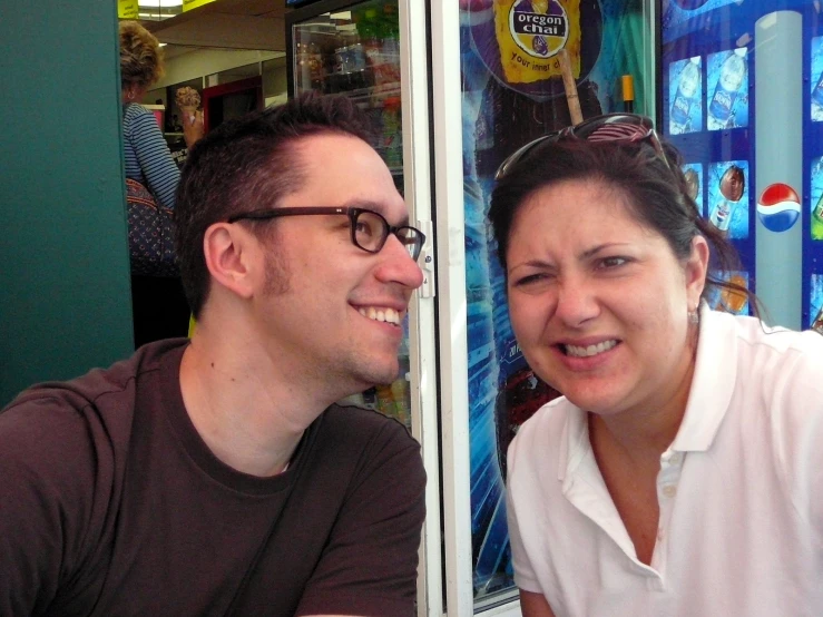 two people sitting at a table in front of a store