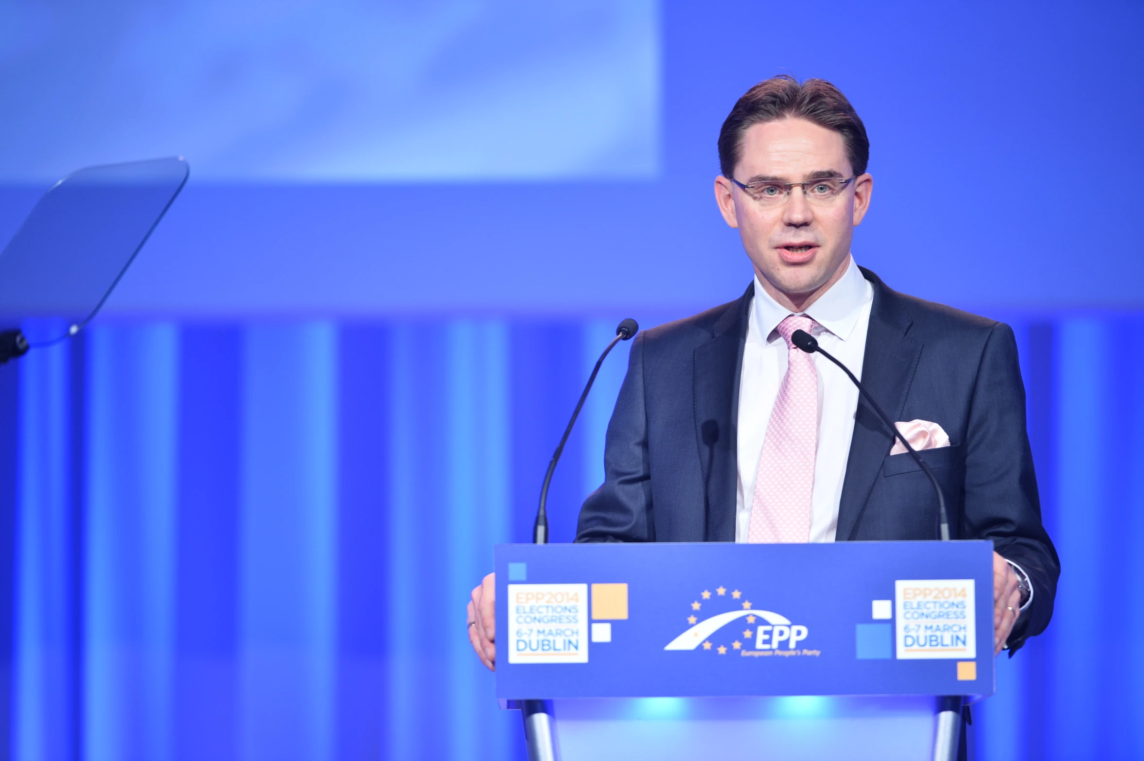 man in suit and tie speaking at the podium