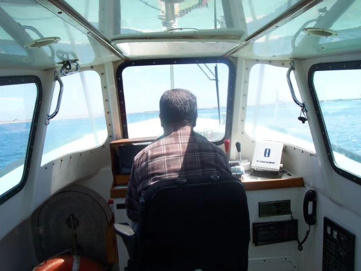 man in the helm of a boat looking out the window