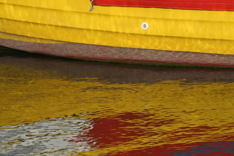 a yellow and red boat sitting on the shore