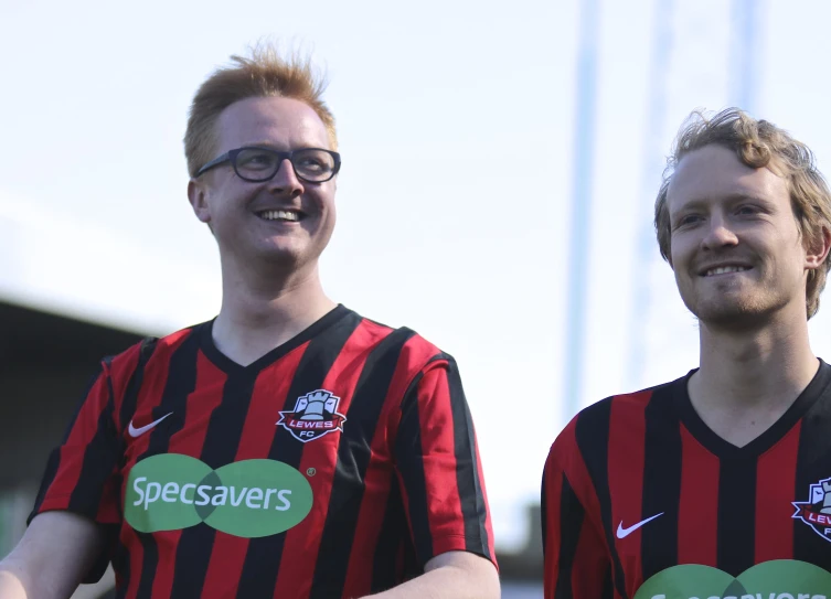 two young men wearing black and red shirts are smiling