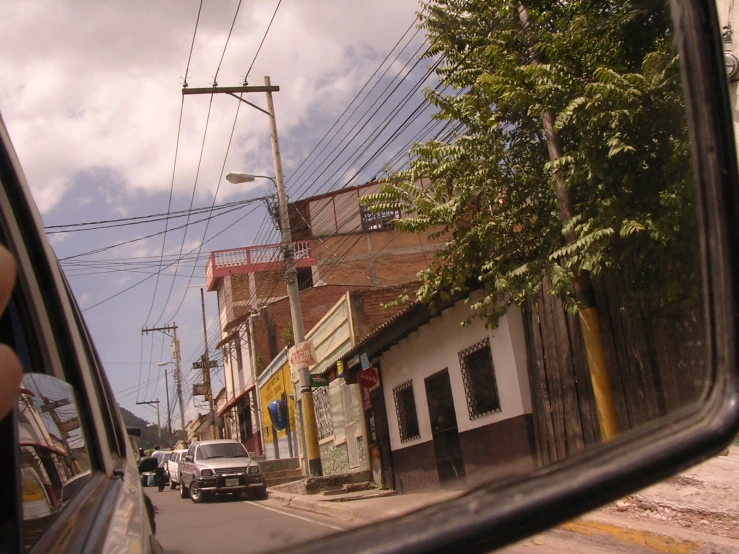 the rear view mirror of a car in front of a building with a large power line above it