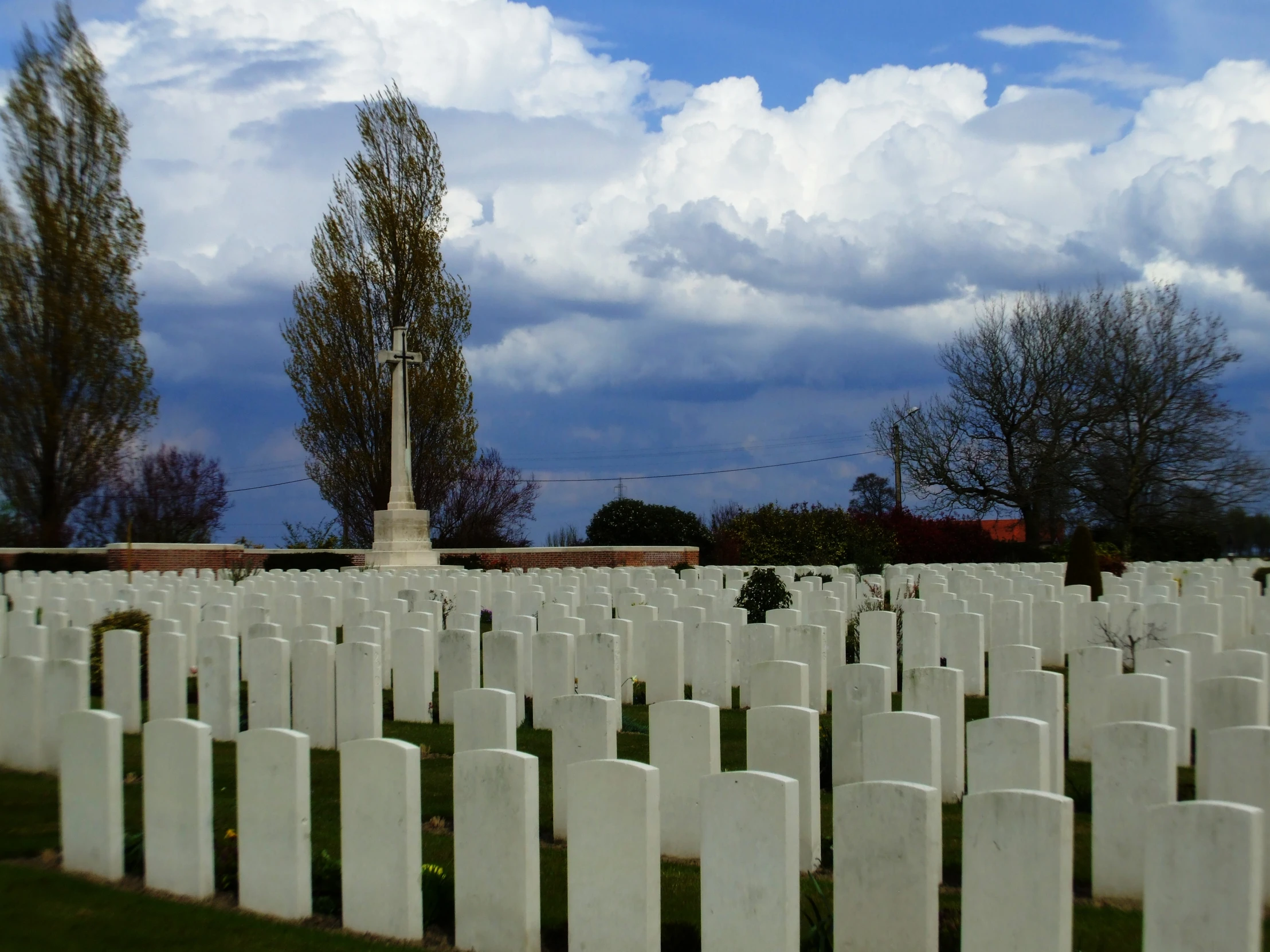 an array of headstones stand tall against the cloudy sky