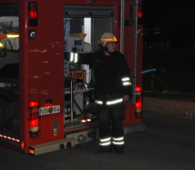 a firefighter standing inside a fire truck at night