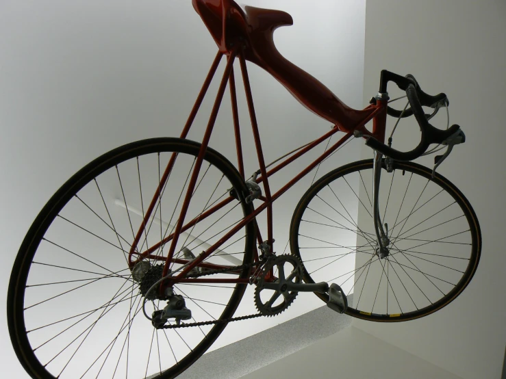 a tall red bike sitting up against a white wall