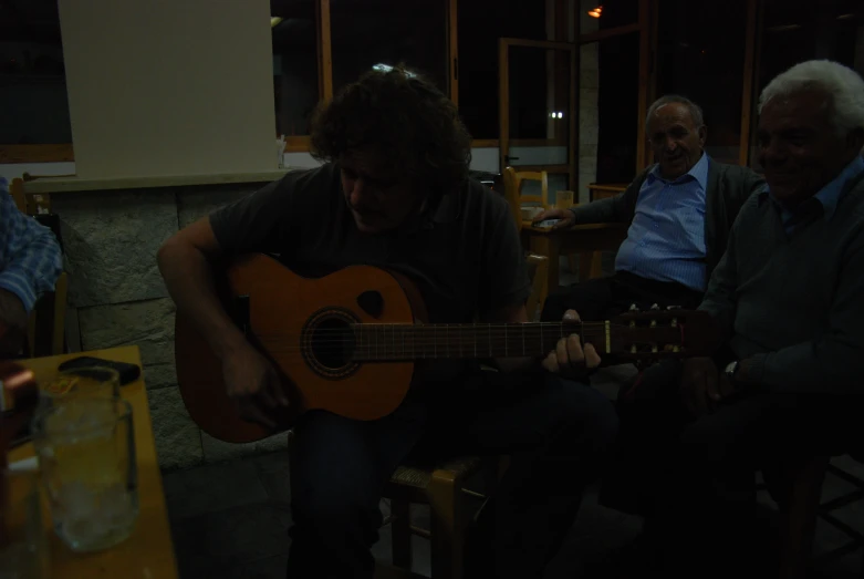 a man sitting in a restaurant holding a guitar