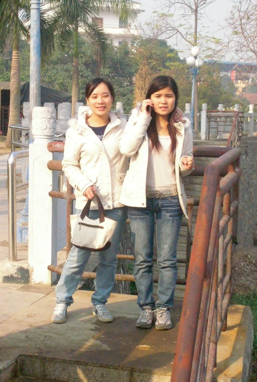 two young asian women standing together on a railing