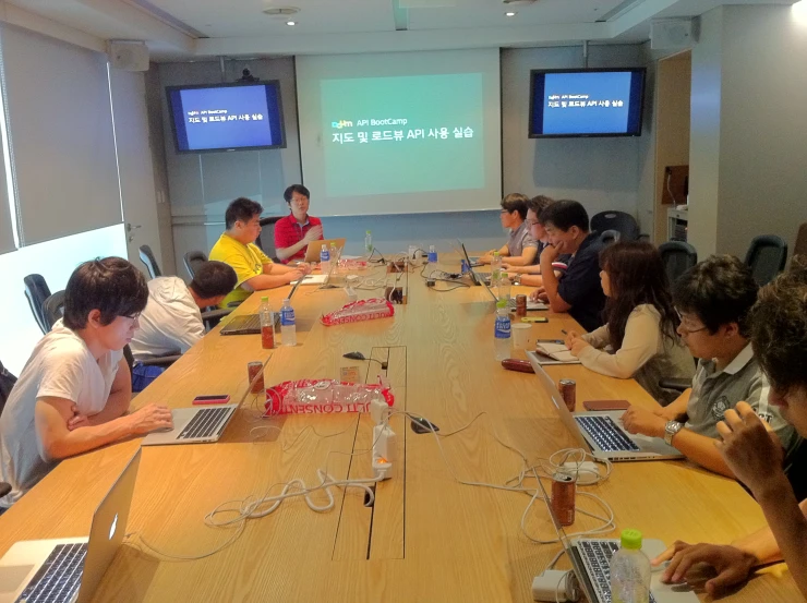 a group of people sitting around a table with laptops