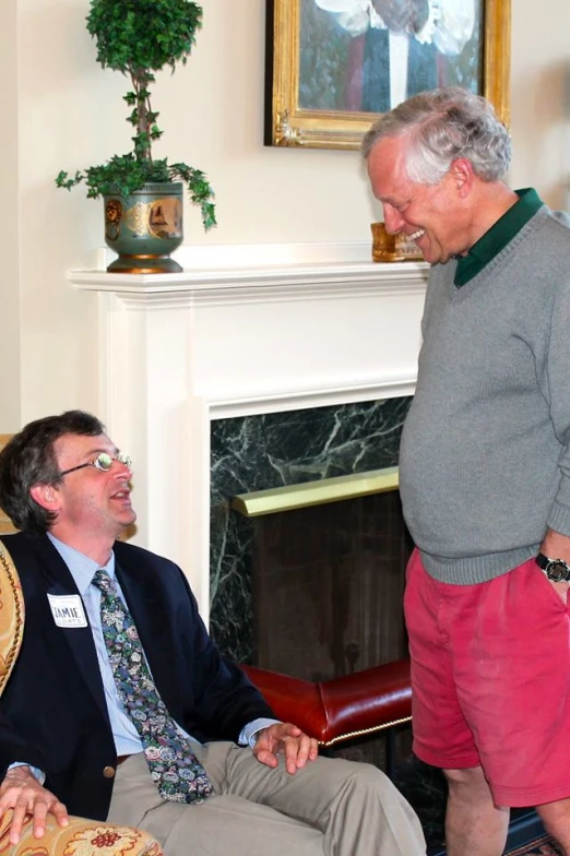 man sitting in the back of an antique chair laughing while another man holds his foot up