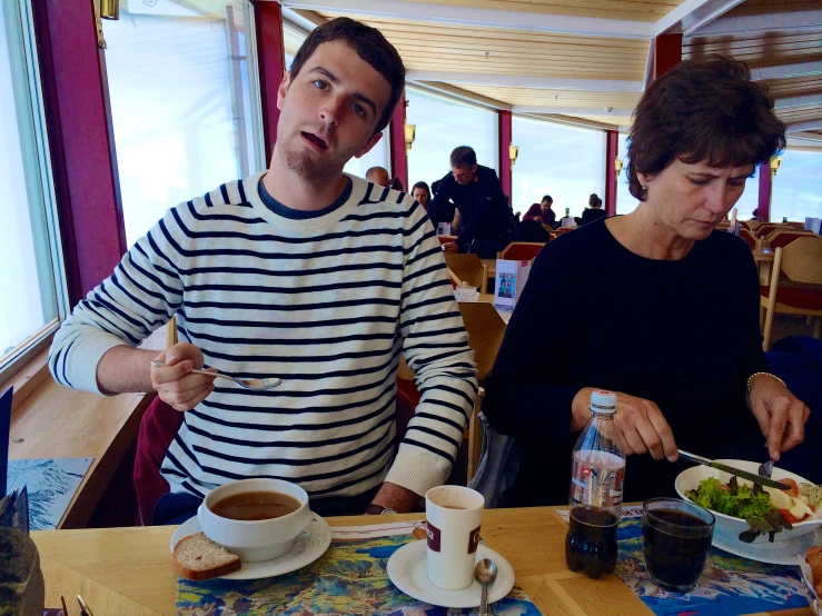 two people sitting at a table with food in bowls