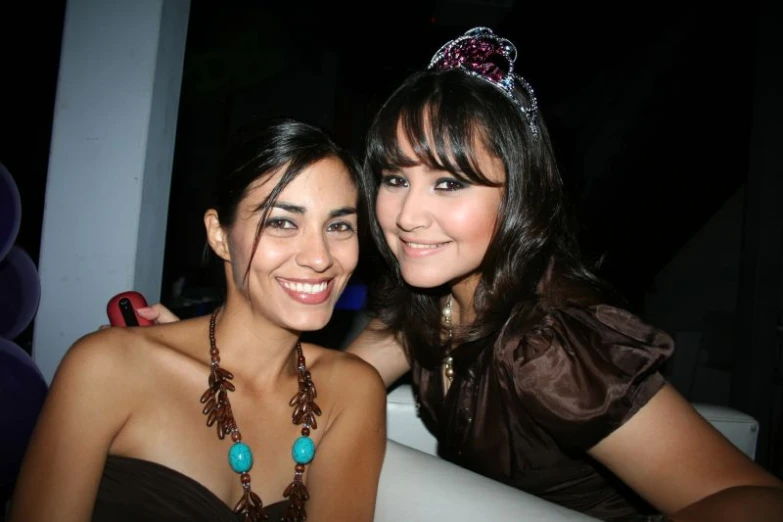 two women posing for a picture together with beads and tiaras