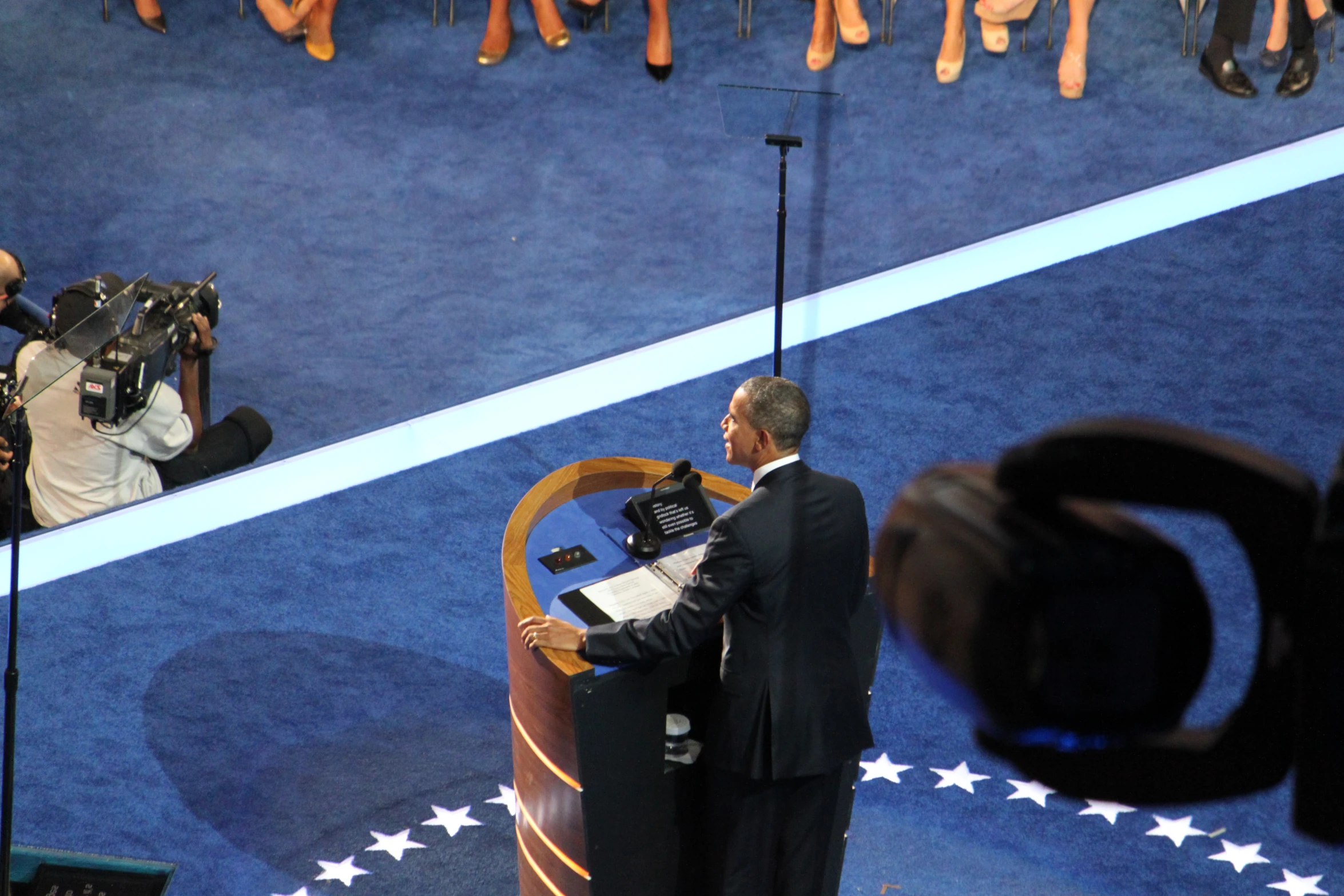 politician giving a speech on stage with cameramen