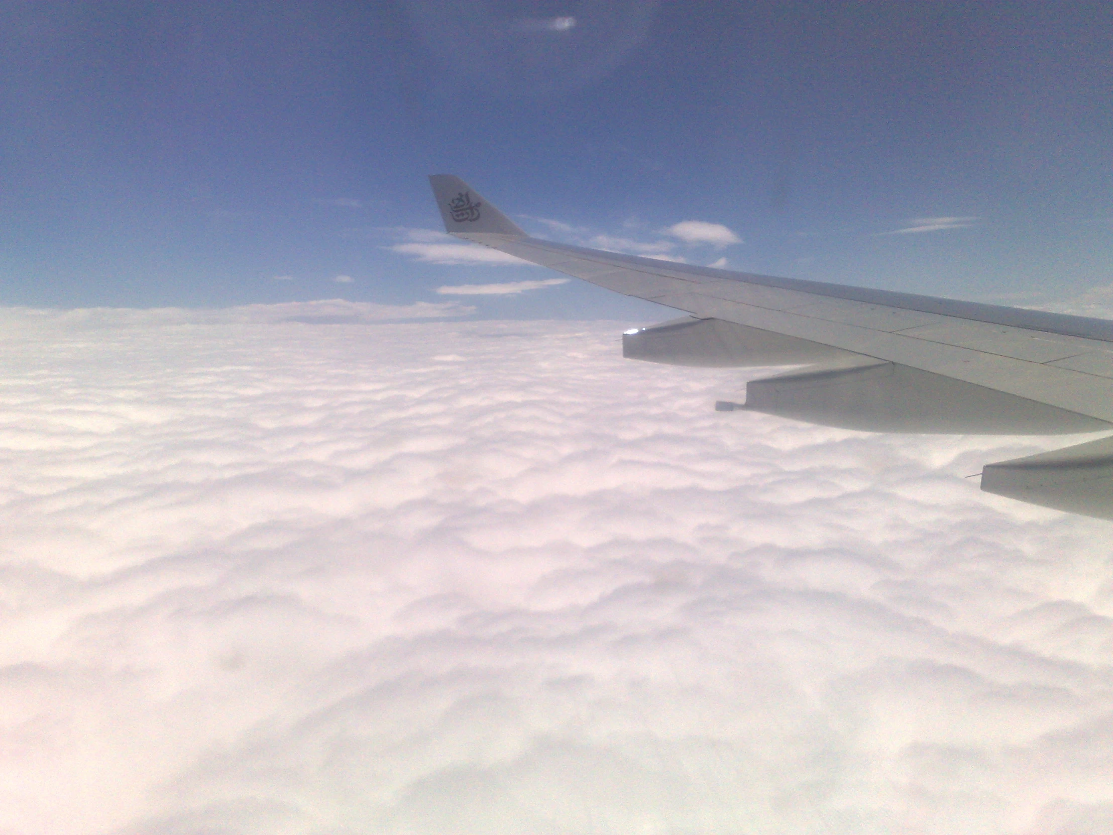 airplane wing above the clouds in the sky