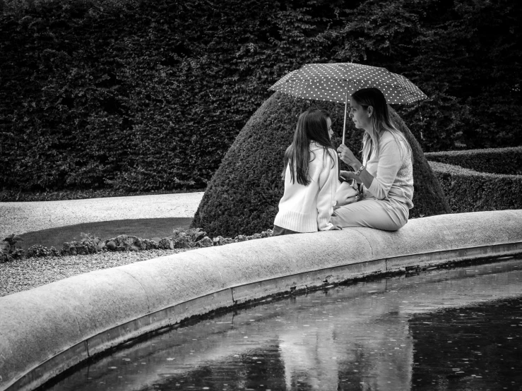 black and white pograph of a couple kissing under an umbrella by a fountain