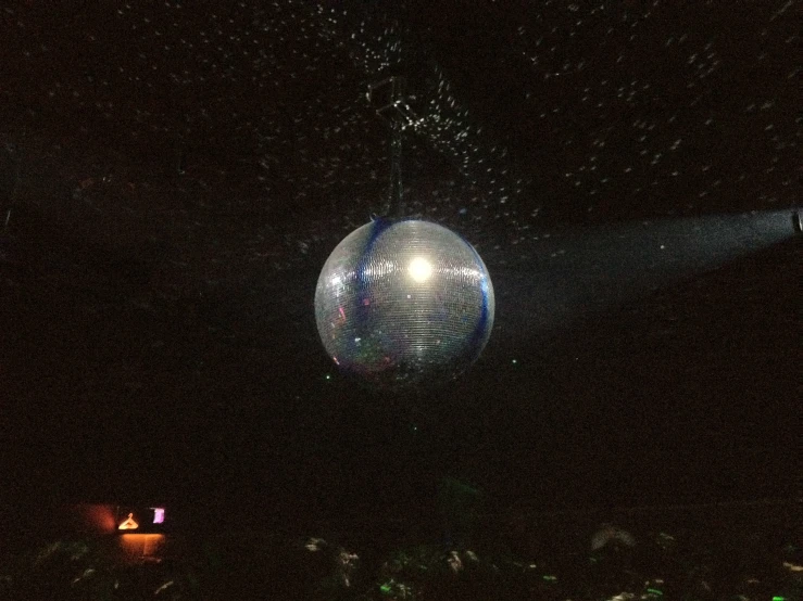 a big silver ball hanging from a dark night sky