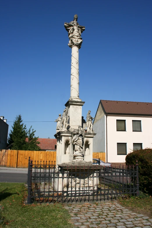 a statue is sitting in the yard next to a fence