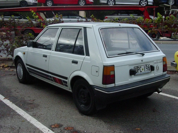 white and black car in parking space between parked cars