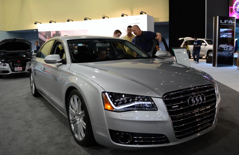 two men stand next to an audi car