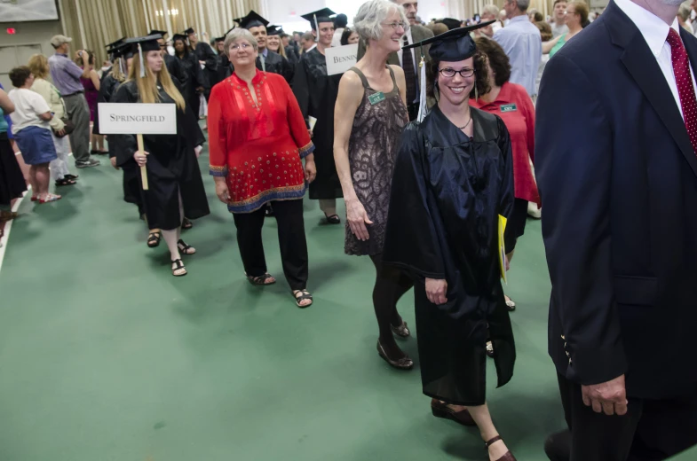 many people are waiting to be dressed in graduation gowns