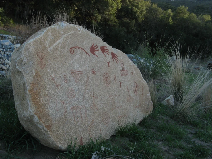 a large rock sitting on top of a grass covered field