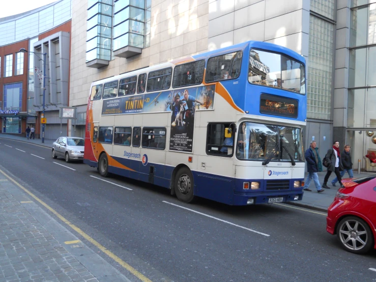 a white and blue double decker bus parked next to some buildings