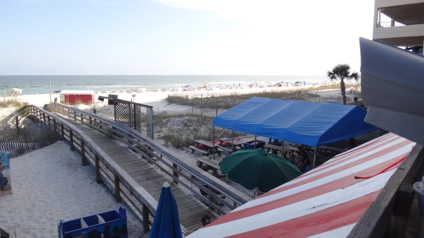 a boardwalk at the beach next to some umbrellas