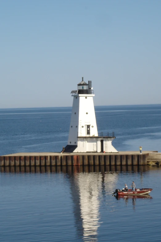 a lighthouse on a pier with a rowboat