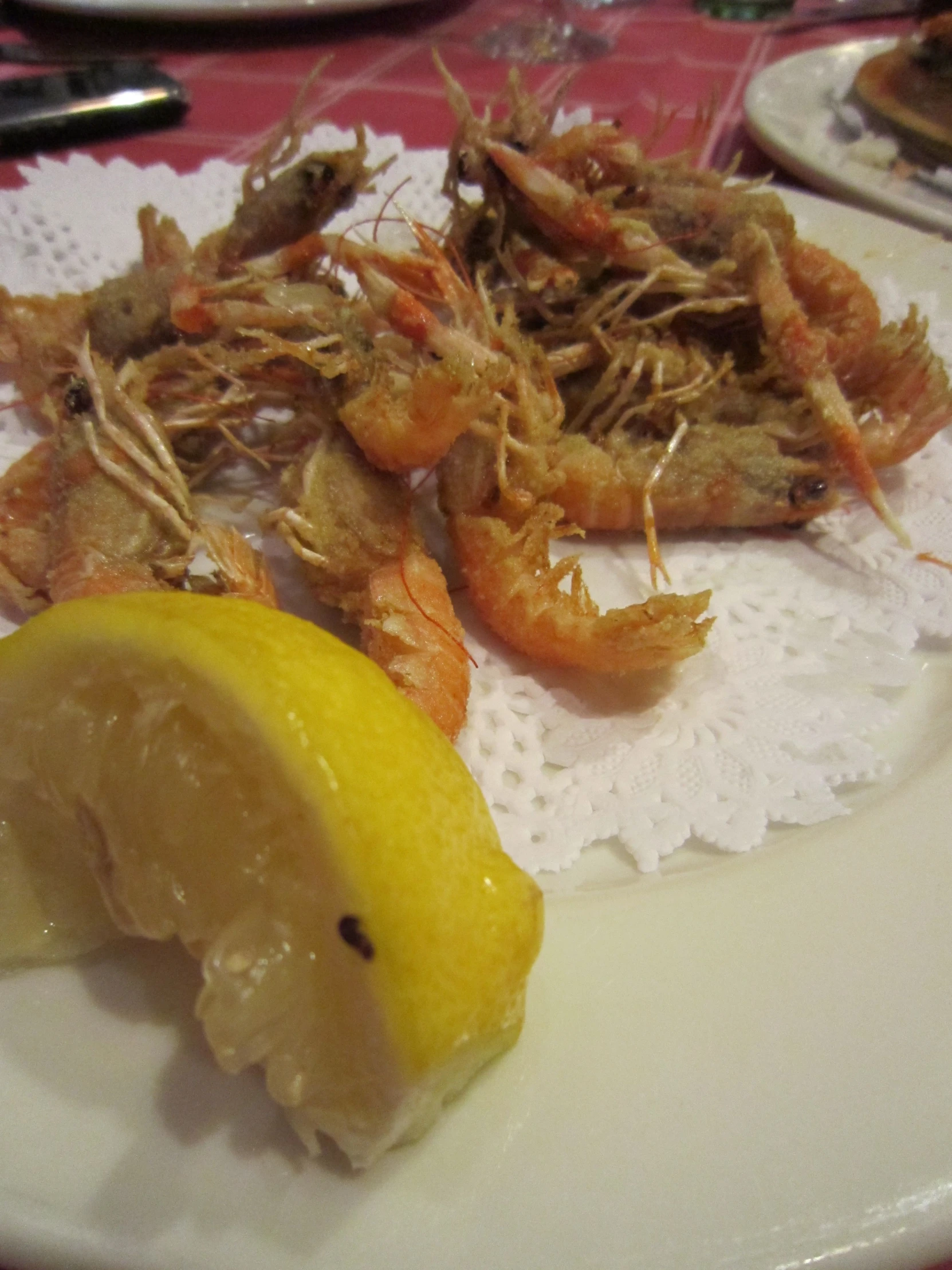 a plate of shrimp, lime and a lemon wedge