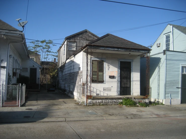 the front of a white, rundown house in an older neighborhood