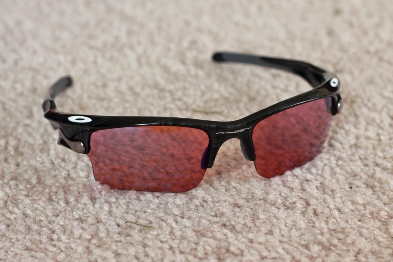 a pair of black and red sunglasses laying on top of a carpet
