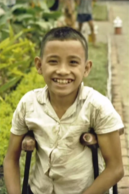 a smiling boy wearing a school uniform with back to back backpacks