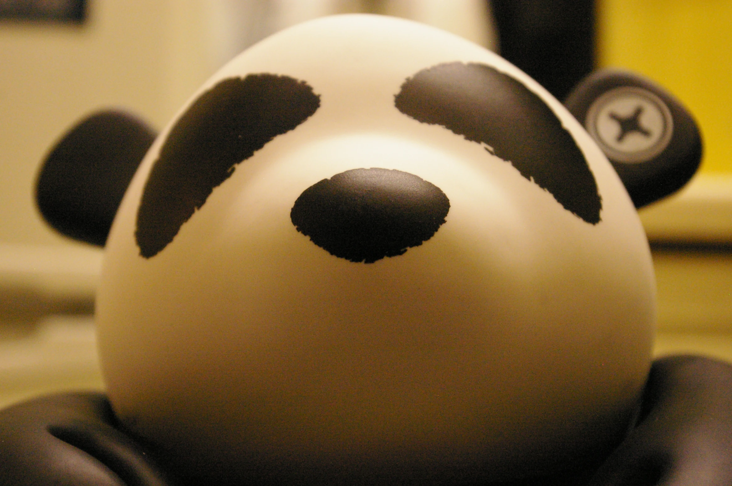 a close up of a toy of a panda bear with the face painted black