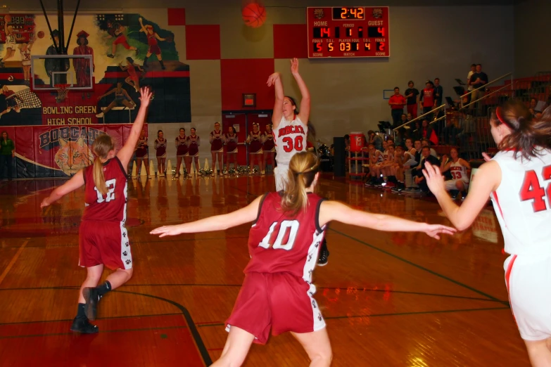 a group of girls playing basketball on a wood floor