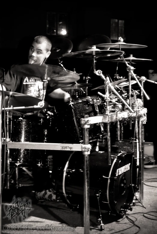 a man with a microphone sits behind drums