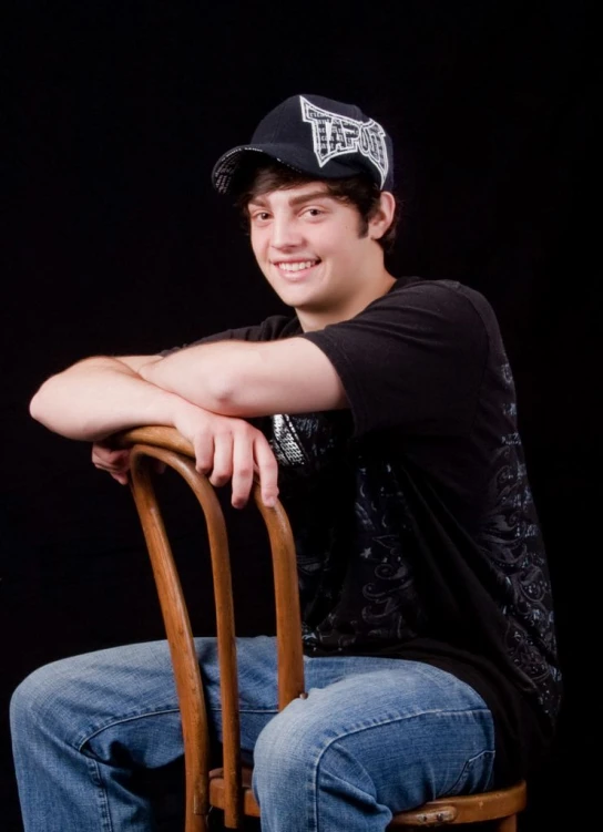 a man sitting in a chair wearing a black hat