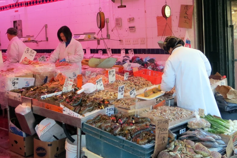 several people standing at a table selling food