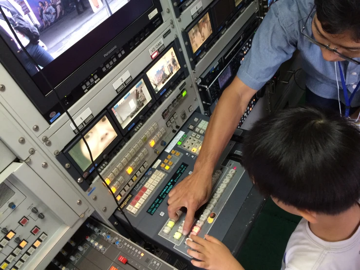 a man and a boy looking at the control panel of a sound mixing desk