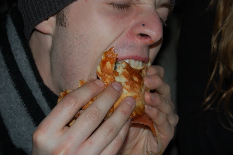 a person taking a bite of pizza off his mouth