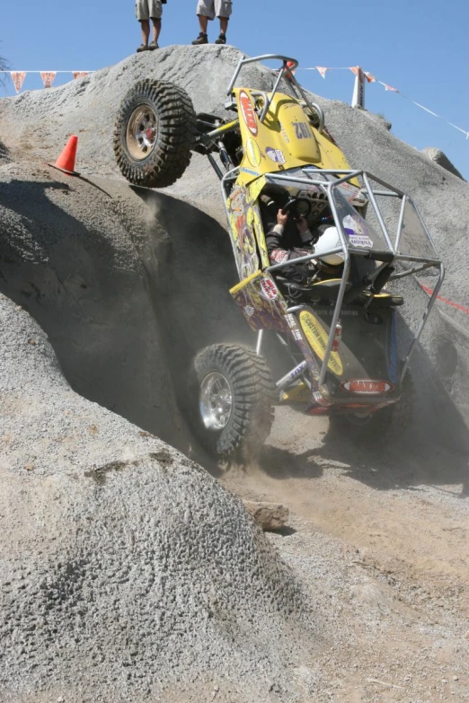 some people in a yellow car on a big rock