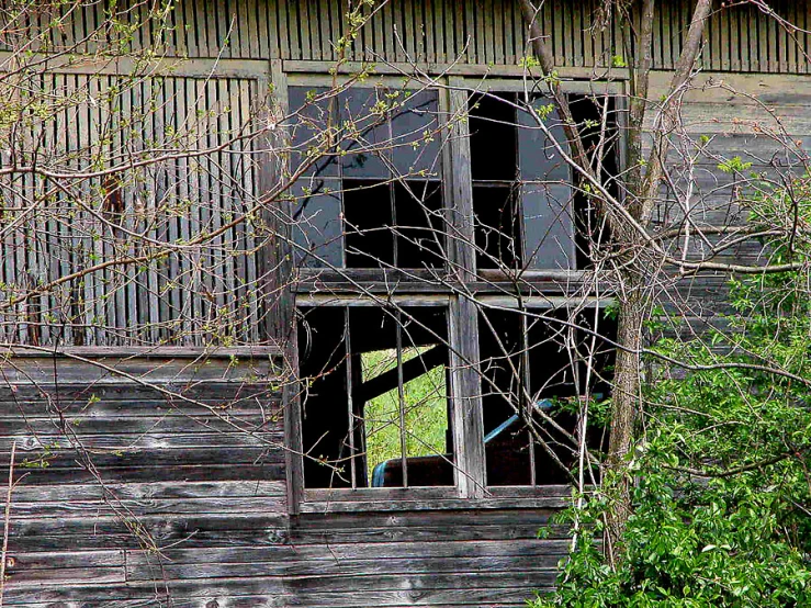 an open window with peeling paint on the outside of a run down barn