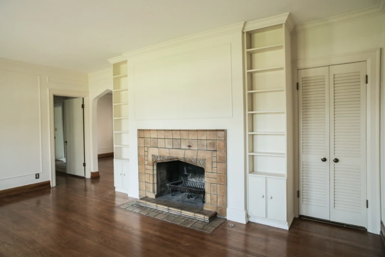an empty room with a fireplace and shelves above it