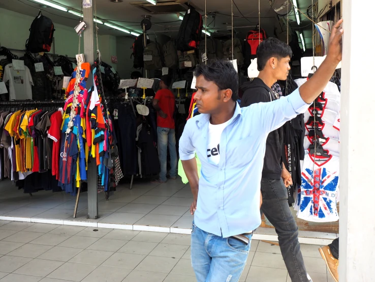 two boys are standing near the clothes stand