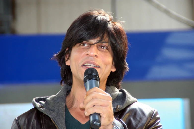 the singer has dark brown hair and is holding a microphone