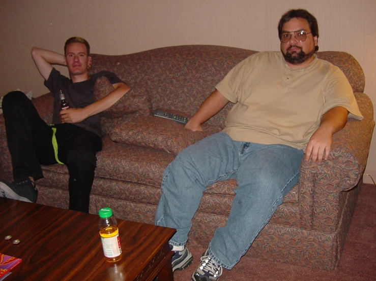 two men sitting on top of a couch near a table