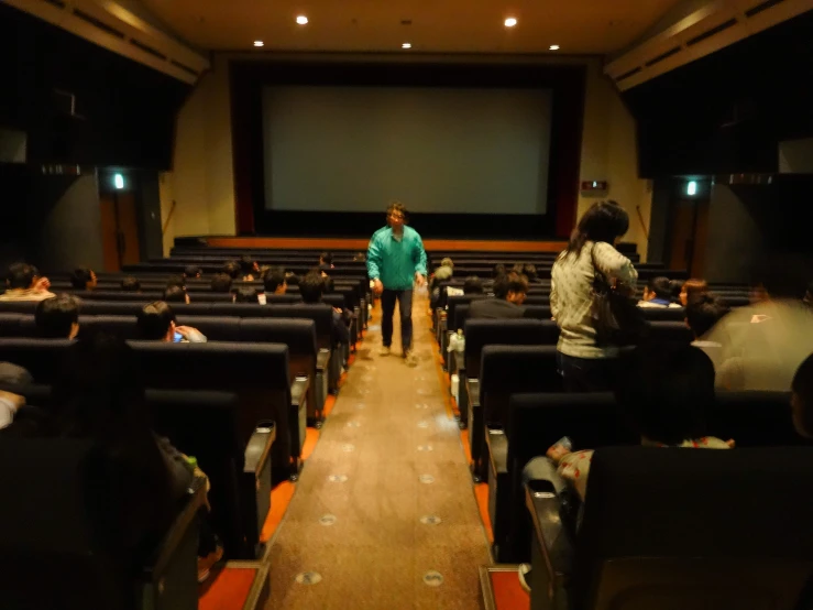 people watching an audience in a auditorium with a screen