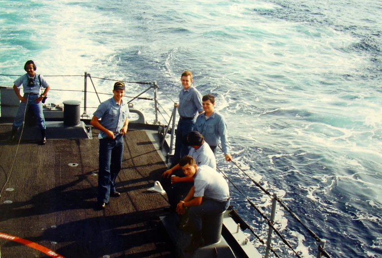 six men are hanging out at the side of a boat