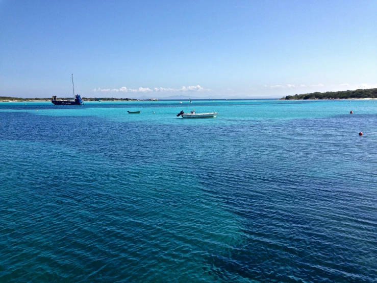 a small boat on the ocean surrounded by many smaller boats