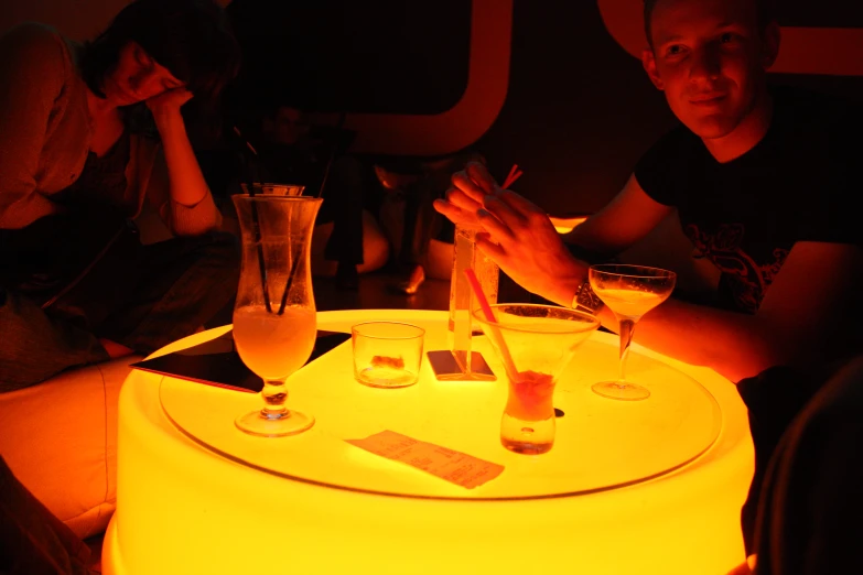 two young men sitting in front of a table covered in drinks