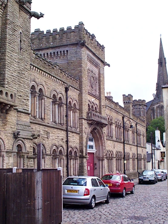 cars parked in front of old buildings on cobblestone road