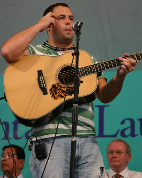 man holding acoustic guitar in right hand at microphone